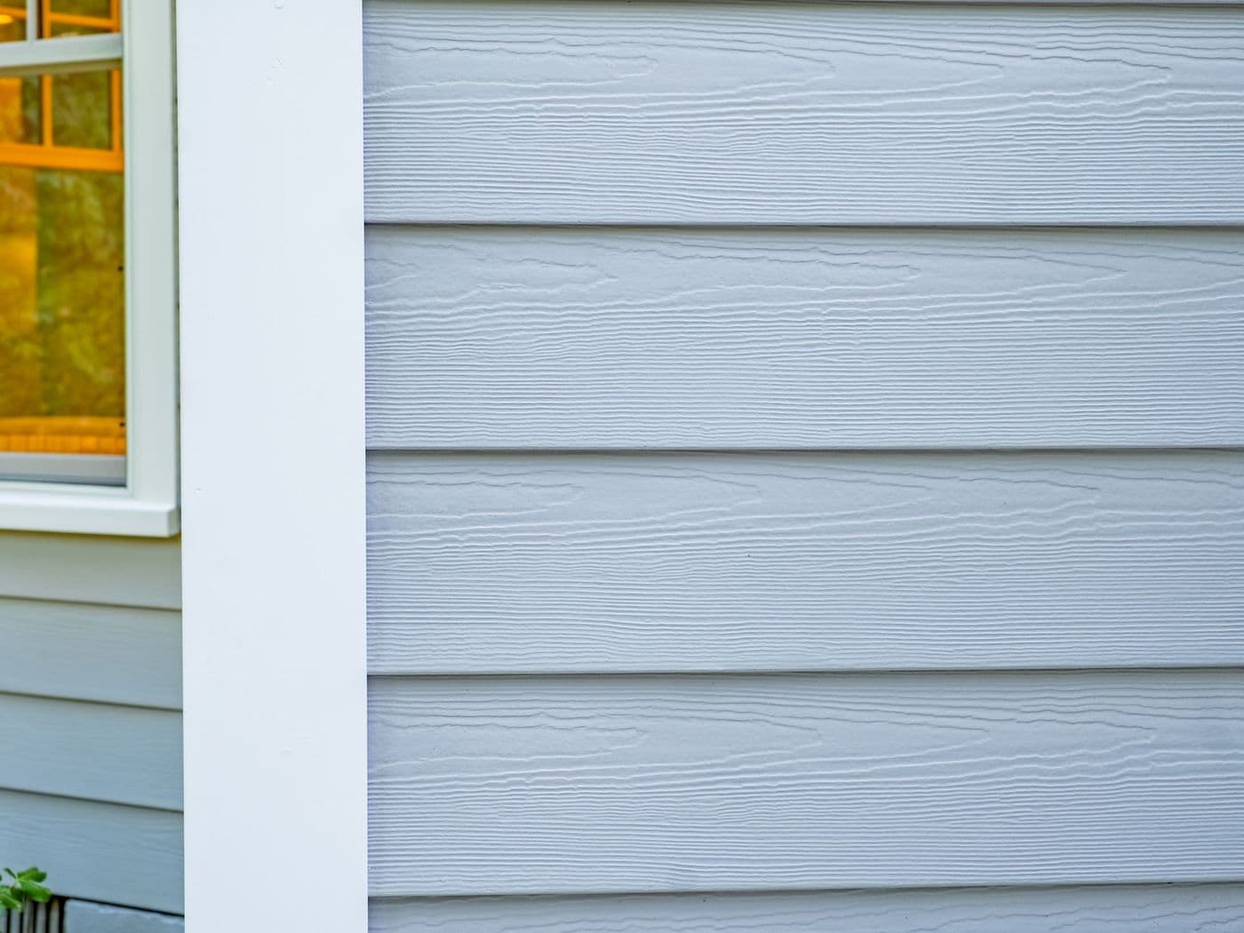 Close-up of grey horizontal lap siding boards showing a cedarmill woodgrain texture, beside a white window trim.
