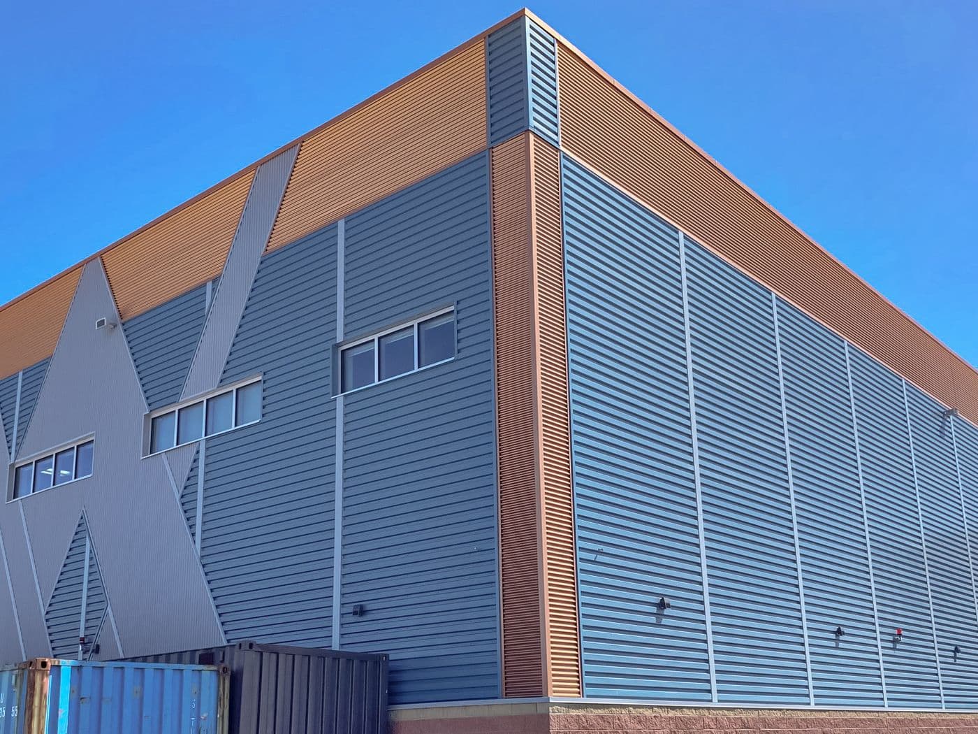 Angular commercial building corner clad in grey and copper-toned 636 wall metal panels.