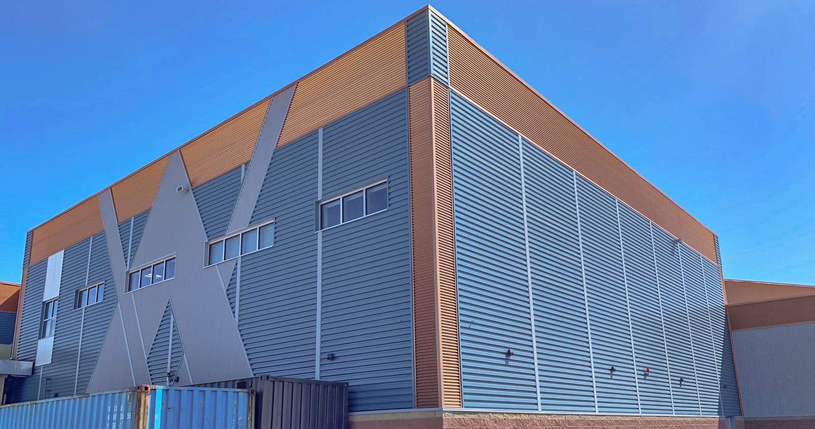 Angular commercial building corner clad in grey and copper-toned 636 wall metal panels.